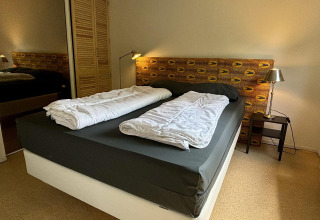 Dormitorio en Tiny Lodge Basic, Bungalowpark Het Verscholen Dorp, Países Bajos, con cama doble y lámparas.