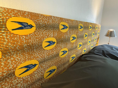 Farverigt hovedgærde med fuglemotiver og gule cirkler på Tiny Lodge Basic ved Het Verscholen Dorp.