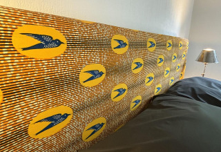 Farverigt hovedgærde med fuglemotiver og gule cirkler på Tiny Lodge Basic ved Het Verscholen Dorp.