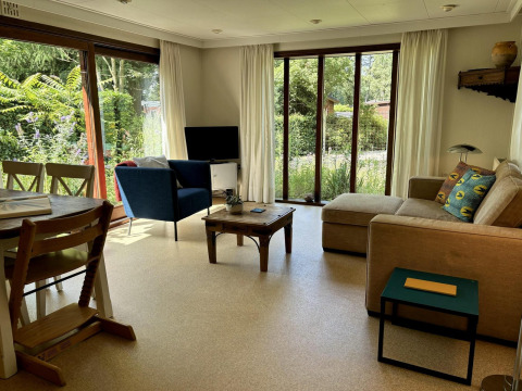 Stue i Tiny Lodge Basic på Bungalowpark Het Verscholen Dorp i Holland, med sofa, stol og udsigt til have.