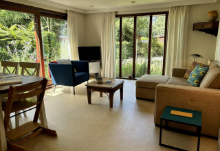 Stue i Tiny Lodge Basic på Bungalowpark Het Verscholen Dorp i Holland, med sofa, stol og udsigt til have.