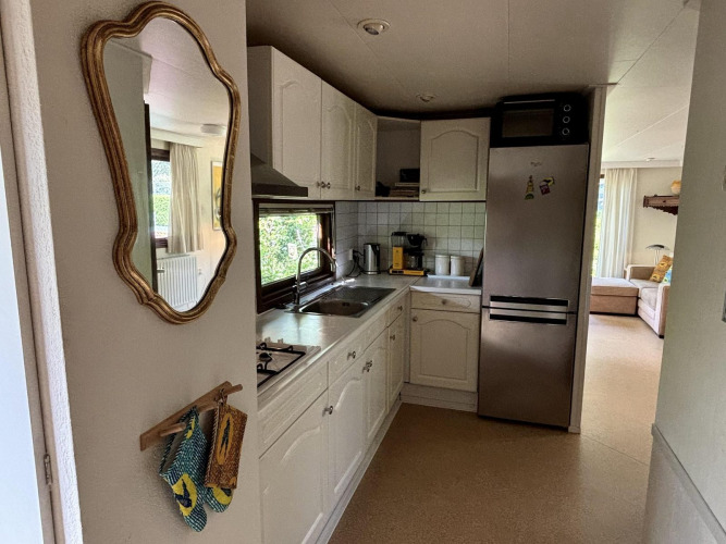 Zona de cocina compacta en Tiny Lodge Basic de Bungalowpark Het Verscholen Dorp, Países Bajos, con armarios blancos.