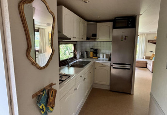 Piccola cucina nella Tiny Lodge Basic al Bungalowpark Het Verscholen Dorp, Paesi Bassi, con mobili bianchi.