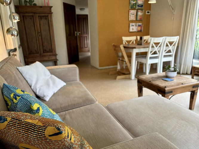 Salón acogedor en Tiny Lodge Basic con sofá, cojines coloridos, mesa de madera y comedor en Het Verscholen Dorp.