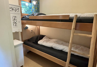 Kamer met stapelbed, houten ladder en raam in Tiny Lodge Basic van Bungalowpark Het Verscholen Dorp, Nederland.