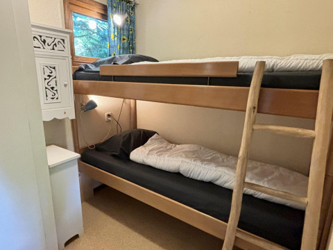 Habitación con litera, escalera de madera y ventana en el Tiny Lodge Basic de Bungalowpark Het Verscholen Dorp.