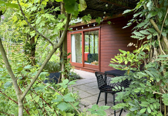 Accogliente Tiny Lodge Basic in legno con ampia porta a vetri e terrazza immersa nel verde.