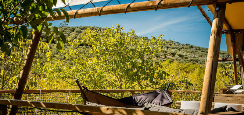 Blick aus dem Desert Lodge Safarizelt mit privatem Bad auf Camping Pian di Boccio, Italien, umgeben von Natur.