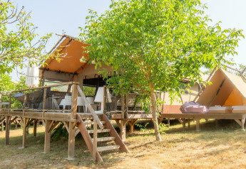 Tienda safari Desert Lodge con baño privado, terraza de madera, árboles verdes y ambiente soleado.