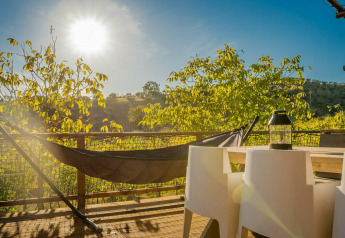 Terrazza soleggiata della tenda safari Desert Lodge al Camping Pian di Boccio, Italia, con amaca e tavolo.