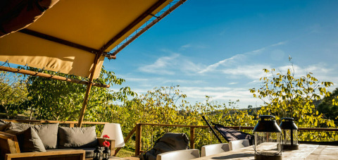 View from the Desert Lodge safari tent with private bathroom at Camping Pian di Boccio, Italy, on a sunny day.