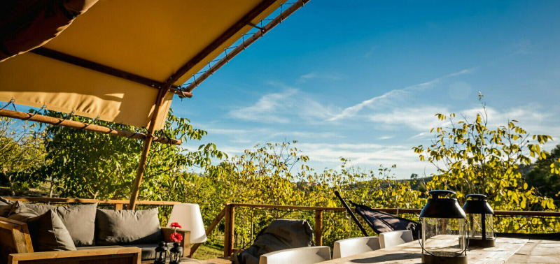 Terrasse im Desert Lodge Safari-Zelt mit privatem Bad auf dem Camping Pian di Boccio, Italien, bei Sonnenschein.