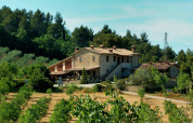 En stor bondegård omgivet af grønne marker og skov ved Camping Pian di Boccio i Umbrien, Italien.