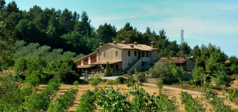 Grote stenen boerderij te midden van groen bij Camping Pian di Boccio, een vakantiepark in Umbrië, Italië.