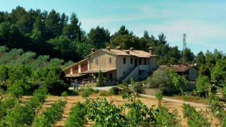 Casa rural de piedra entre árboles en el Camping Pian di Boccio, un parque vacacional en Umbría, Italia.