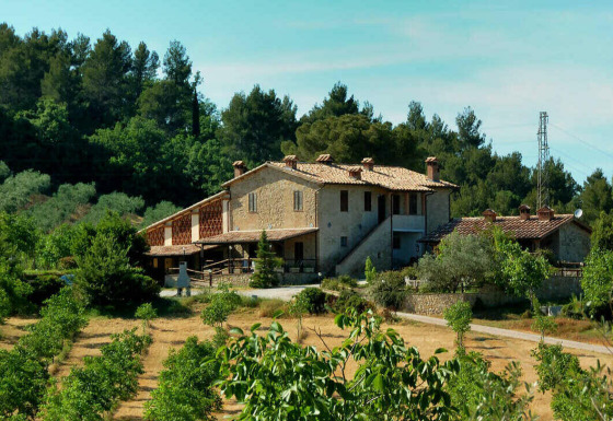Large stone farmhouse surrounded by lush greenery at Camping Pian di Boccio holiday park in Umbria, Italy.