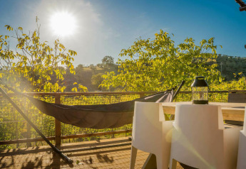 Solrig terrasse med hængekøje og stole ved Desert Lodge safari telt på Camping Pian di Boccio, Italien.