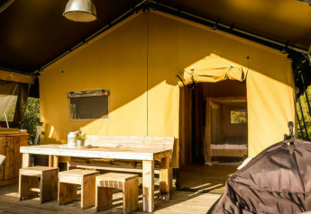 Safari Lodge tent op Camping Pian di Boccio in Italië met houten meubilair en zonnige ingang.