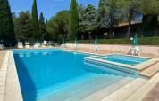Udendørs swimmingpool med afslapningsområde og liggestole på Camping Pian di Boccio i Umbrien, Italien.