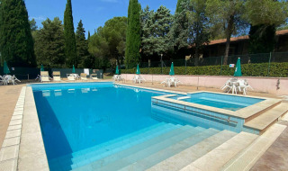Udendørs swimmingpool med afslapningsområde og liggestole på Camping Pian di Boccio i Umbrien, Italien.
