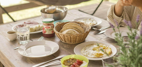 Mesa de desayuno en la tienda Safari Lodge de Camping Pian di Boccio, Italia, con pan, mermelada y huevos.