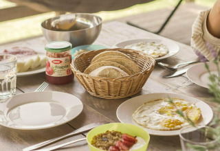 Mesa de desayuno en la tienda Safari Lodge de Camping Pian di Boccio, Italia, con pan, mermelada y huevos.