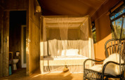 Cozy safari tent interior with a canopy bed and private bathroom at Camping Pian di Boccio in Italy.