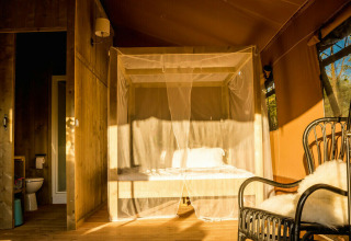 Hyggelig safari teltinteriør med himmelseng og privat badeværelse på Camping Pian di Boccio, Italien.