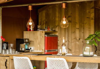 Glampingkeuken met houten meubels en rode koelkast in een safaritent bij Camping Pian di Boccio, Italië.