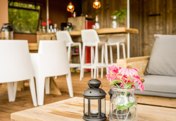 Area interna accogliente di una tenda safari con arredi in legno, fiori in vaso e decorazione moderna.