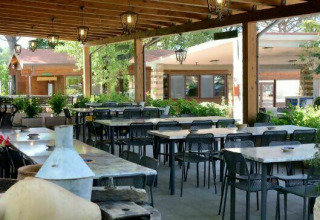 Overdekt terras met tafels en stoelen bij Camping Pian di Boccio in Umbrië, Italië.