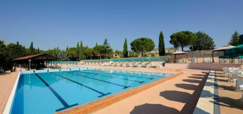 Piscina all’aperto con lettini e ombrelloni al Camping Pian di Boccio, villaggio vacanze in Umbria, Italia.