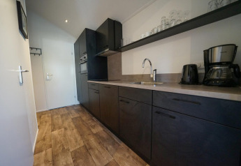 Moderne kitchenette met donkere kasten, houten vloer en koffiezet op een lodge in EuroParcs Veluwemeer, Nederland.