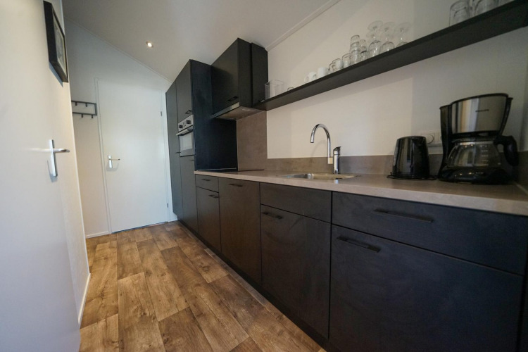Cocina moderna con armarios oscuros, suelo de madera y cafetera en una cabaña de EuroParcs Veluwemeer, Países Bajos.