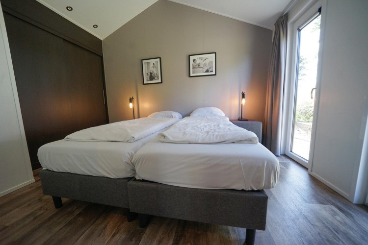 Dormitorio en la cabaña Berkel de EuroParcs Veluwemeer, Países Bajos, con dos camas y decoración moderna.