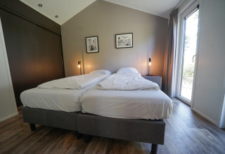 Dormitorio en la cabaña Berkel de EuroParcs Veluwemeer, Países Bajos, con dos camas y decoración moderna.