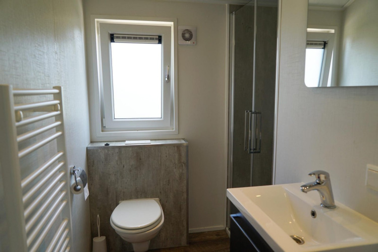 Baño moderno en la cabaña Berkel en EuroParcs Veluwemeer, Países Bajos, con ducha, ventana y lavabo.