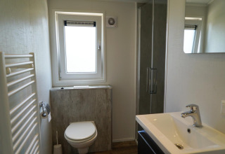 Baño moderno en la cabaña Berkel en EuroParcs Veluwemeer, Países Bajos, con ducha, ventana y lavabo.