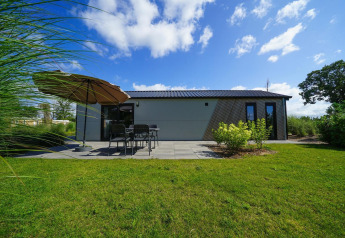 Lodge Berkel bij EuroParcs Veluwemeer in Nederland met terras, tuinstoelen, parasol en grasveld.