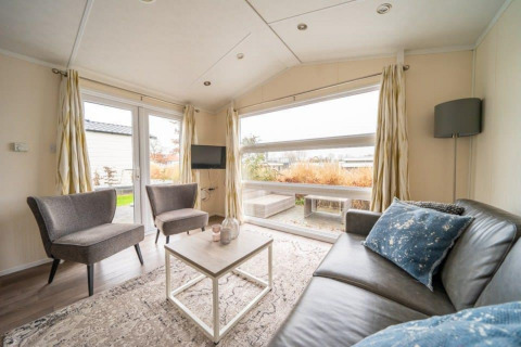 Sala de estar luminosa y moderna en la cabaña Berkel de EuroParcs Veluwemeer, Países Bajos, con ventana grande.