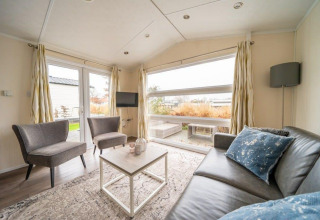 Sala de estar luminosa y moderna en la cabaña Berkel de EuroParcs Veluwemeer, Países Bajos, con ventana grande.