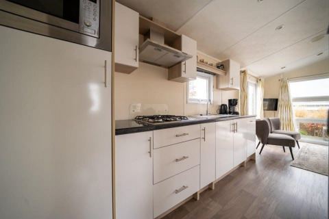 Cocina y sala modernas en la cabaña Berkel de EuroParcs Veluwemeer, con gabinetes claros y ventanales amplios.