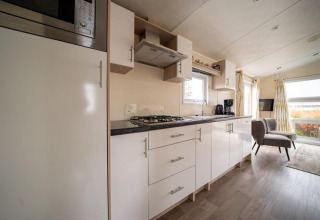 Cocina y sala modernas en la cabaña Berkel de EuroParcs Veluwemeer, con gabinetes claros y ventanales amplios.