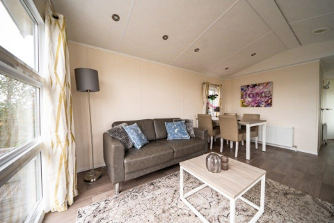 Acogedora sala de estar en Lodge Berkel en EuroParcs Veluwemeer, Países Bajos, con sofá y comedor decorativo.