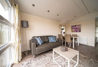 Acogedora sala de estar en Lodge Berkel en EuroParcs Veluwemeer, Países Bajos, con sofá y comedor decorativo.