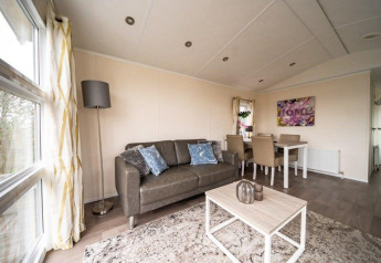 Modernes Wohnzimmer in der Lodge Berkel im EuroParcs Veluwemeer, Niederlande, mit Sofa und Essbereich.