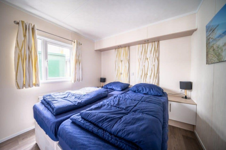 Bedroom with two single beds and blue bedding in Berkel lodge at EuroParcs Veluwemeer, Netherlands.