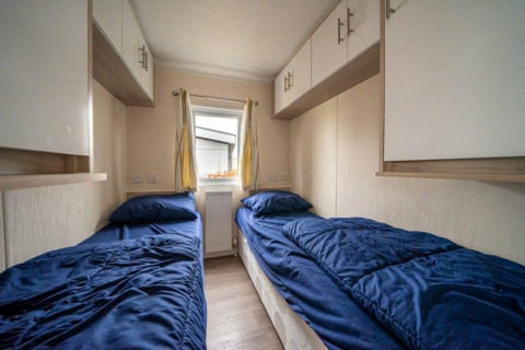 Habitación con dos camas individuales y ropa de cama azul en la cabaña Berkel en EuroParcs Veluwemeer, Países Bajos.