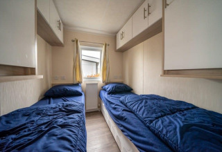 Habitación con dos camas individuales y ropa de cama azul en la cabaña Berkel en EuroParcs Veluwemeer, Países Bajos.