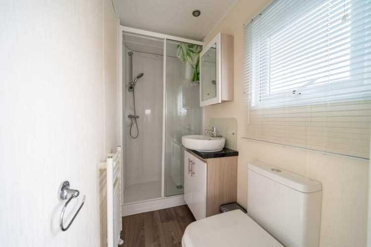 Baño moderno en la cabaña Berkel de EuroParcs Veluwemeer, Países Bajos, con ducha y ventana amplia.